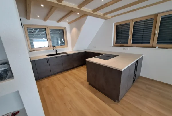 Kücheninsel in Betonoptik Schiefergrau unter Holzbalken – Scholl Küchen Referenz