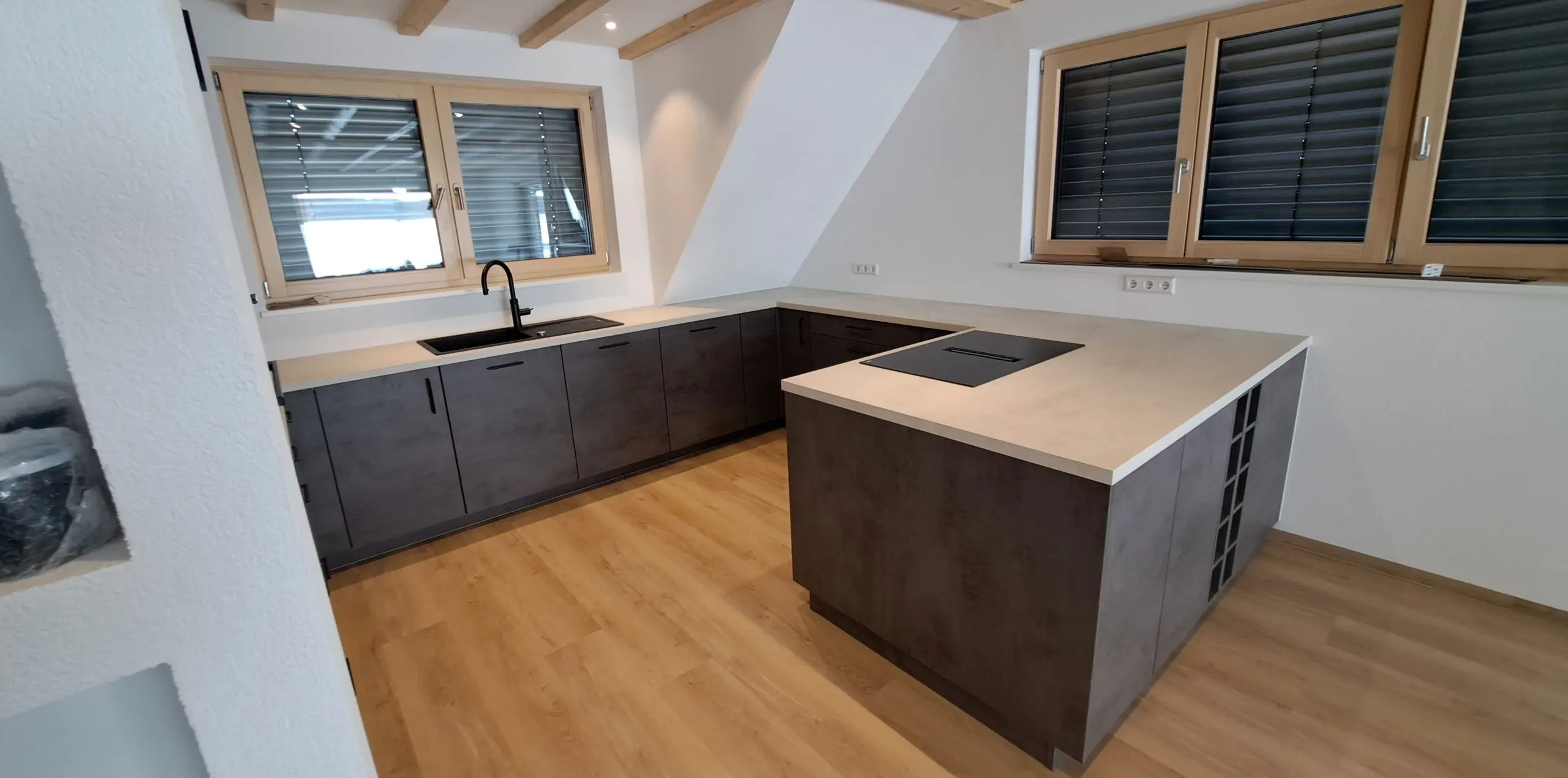 Kücheninsel in Betonoptik Schiefergrau unter Holzbalken – Scholl Küchen Referenz