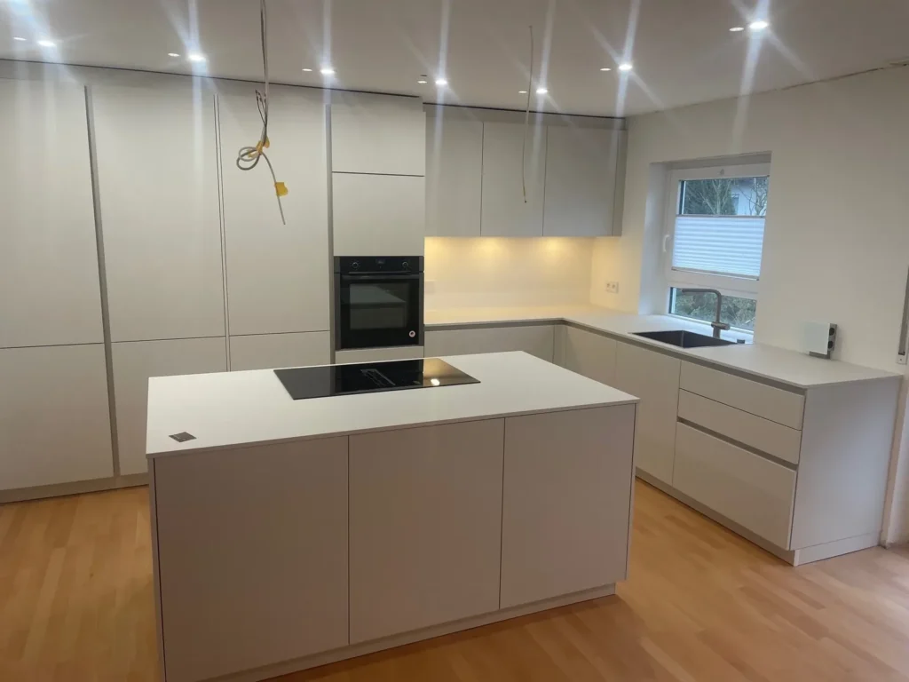 Weiße Küche in Muschelweiß mit Kochinsel und integrierter Architektur – Scholl Küchen Referenz