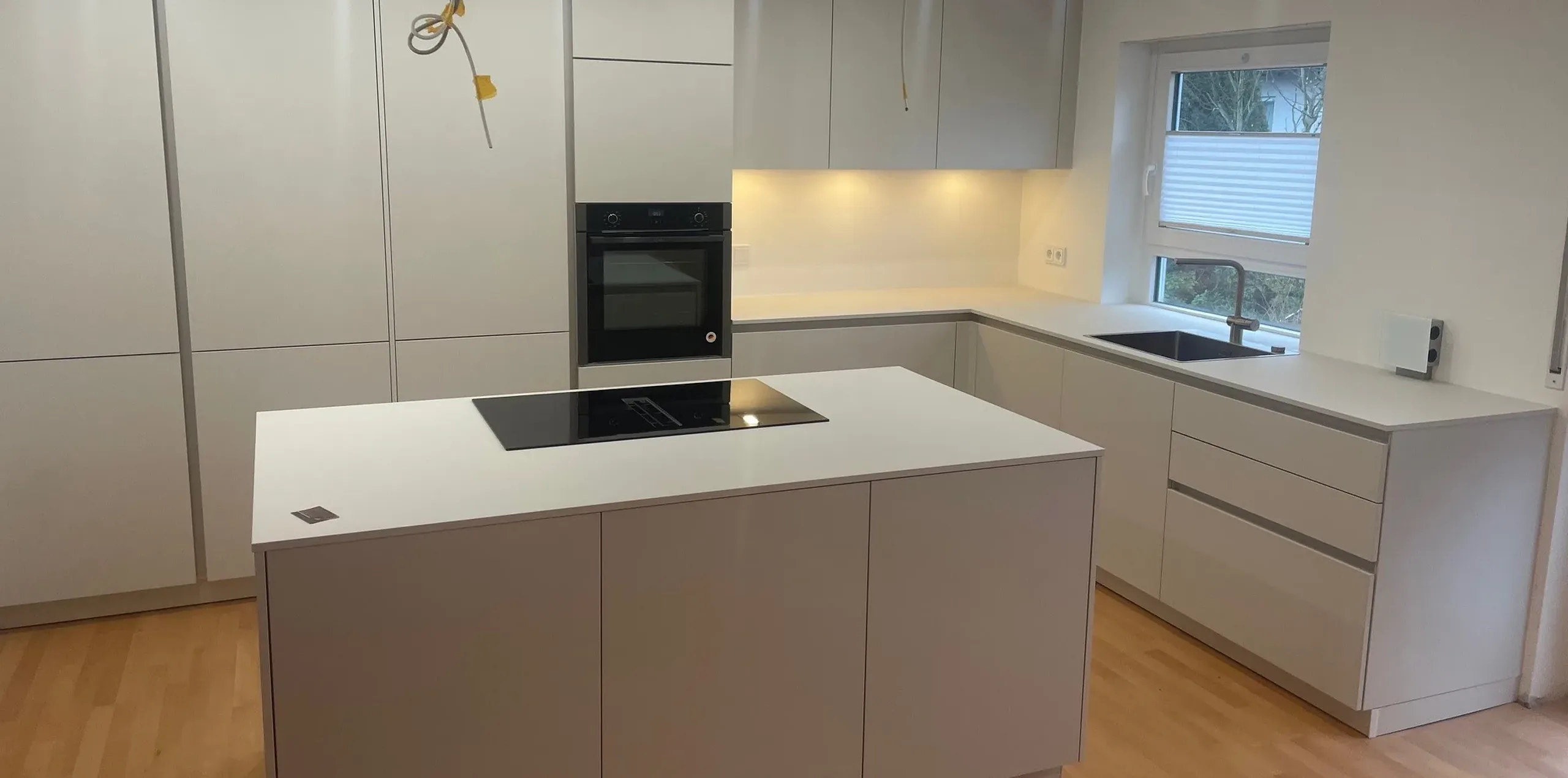 Weiße Küche in Muschelweiß mit Kochinsel und integrierter Architektur – Scholl Küchen Referenz